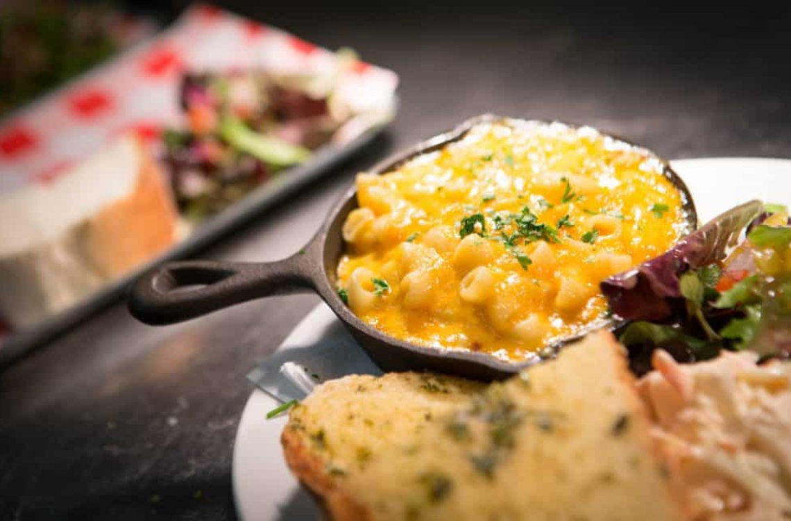Café artysans - Scottish-style macaroni cheese in skillet, topped with herbs, served with garlic bread and side salad.