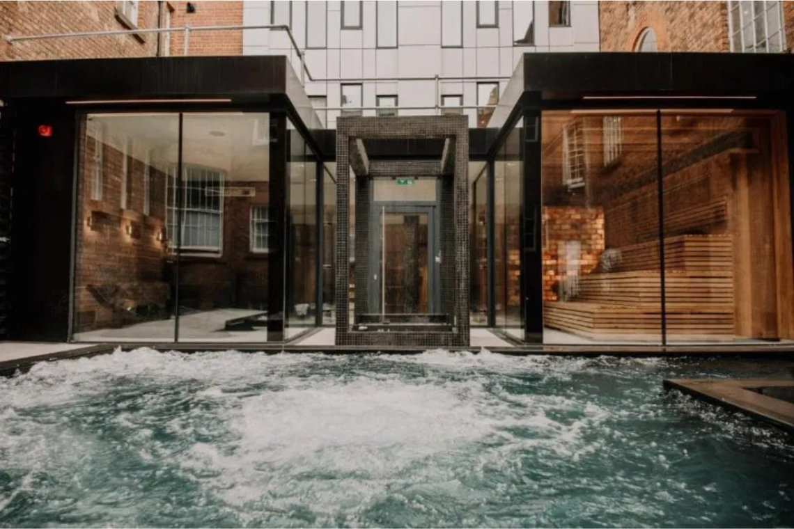 View of outdoor spa pool with modern glass buildings at Hope Street Hotel.