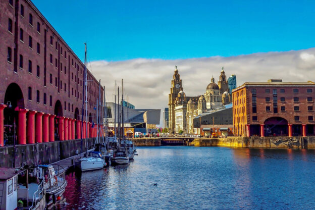 View of Albert Dock in Liverpool with moored boats and historic waterfront buildings.