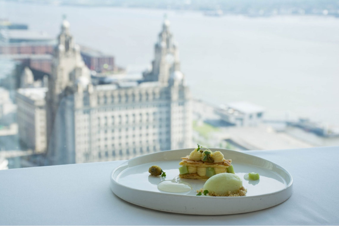 View of gourmet dessert at Liverpool restaurant with Royal Liver Building in background.